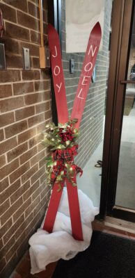 Two crossed skis with "Joy" and "Noel" written on them.