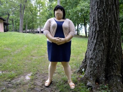 Jennifer in blue sheath dress and tan sweater, with tan sandals.