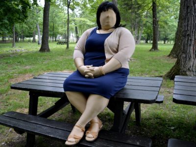 Jennifer in blue sheath dress and tan sweater, with tan sandals.